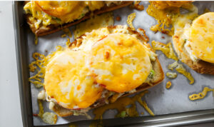 Melted cheese on top of a crab melt open face sandwich.