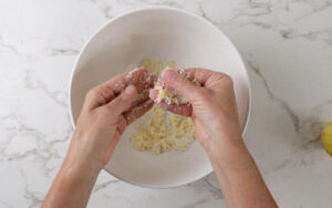 Rubbing lemon zest into sugar in a bowl.