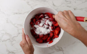 Stirring sugar into fresh strawberries.