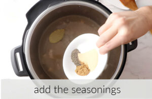 Adding seasonings to the pot with pinto beans.