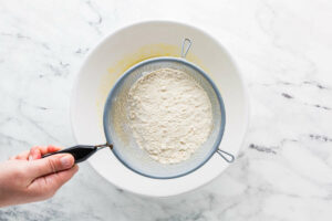 Sifting dry ingredients into pancake batter.