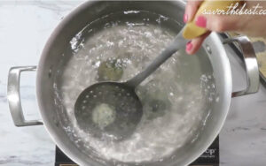 Dipping ricotta malfatti in simmering water.