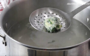 Removing italian ricotta dumplings from the simmering water.