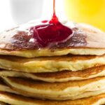 Pouring syrup over ricotta pancakes.