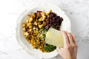Pouring vinaigrette over a roasted cauliflower salad.