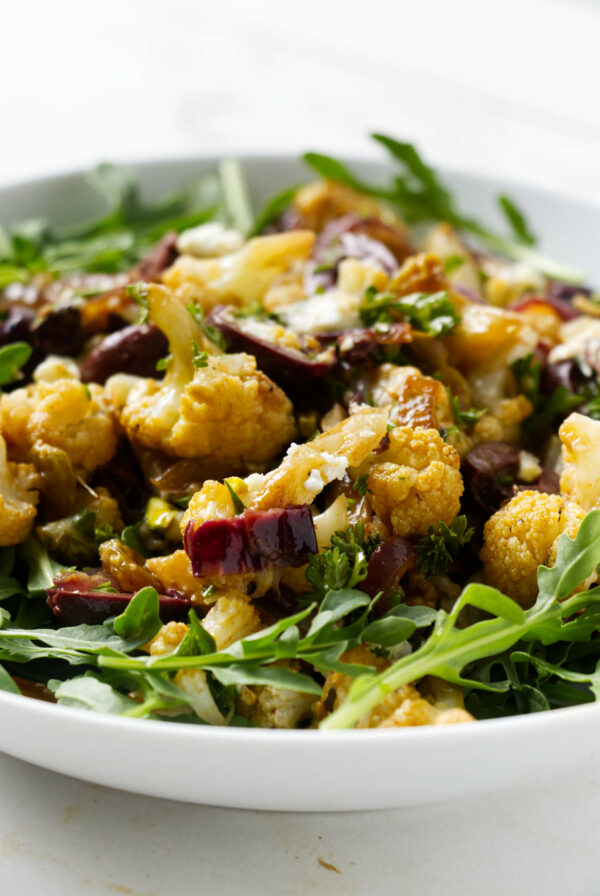 A bowl filled with roasted cauliflower salad tossed with raisins.