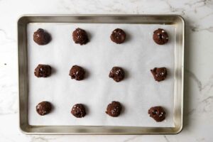 Balls of chocolate sourdough cookie dough on a sheet pan.