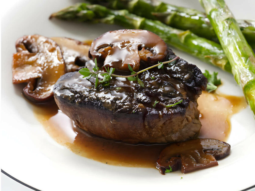 Beef tenderloin medallions with a creamy steak diane sauce on a plate.