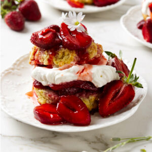 A homemade strawberry shortcake on a plate with fresh strawberries and whipped cream.