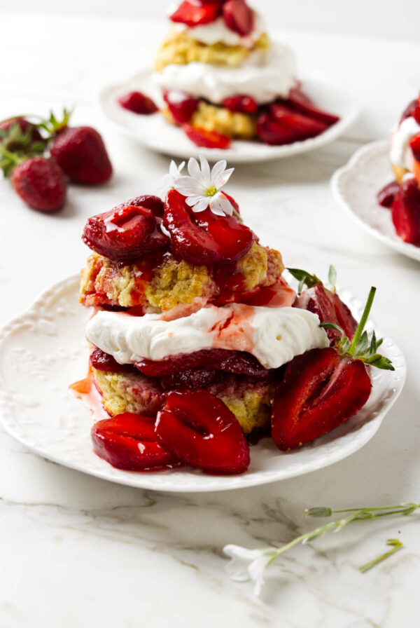 Three individual strawberry shortcake desserts on white plates.