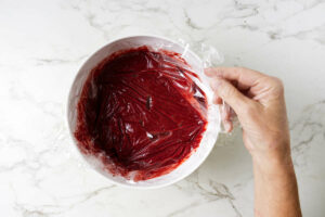 Covering a bowl of strawberry sorbet mixture to chill.