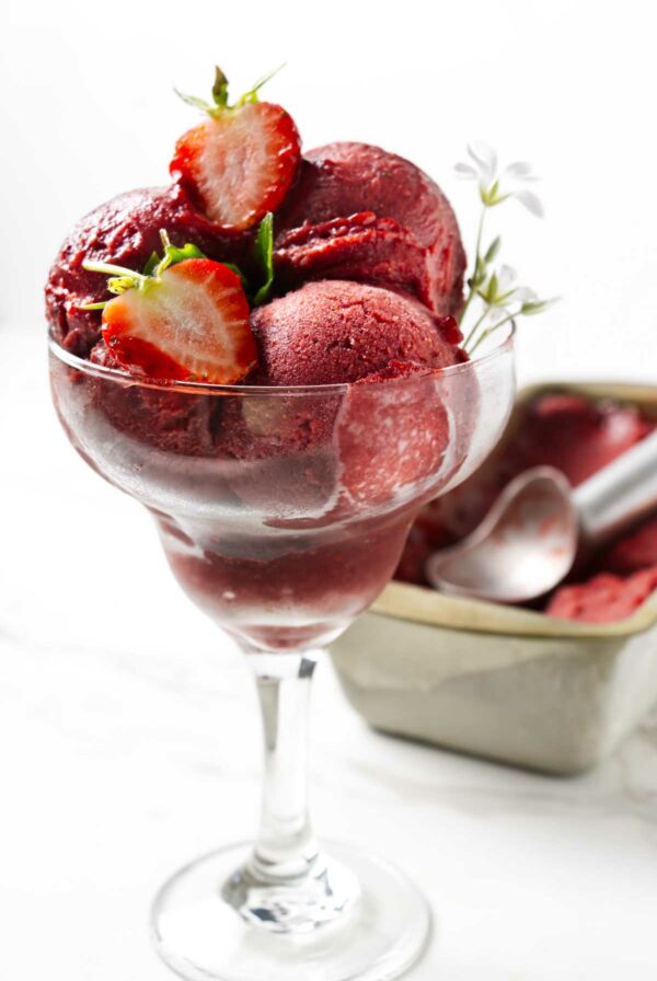 Homemade sorbet made with strawberries in a pretty glass.