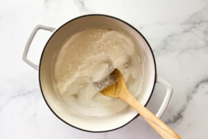 Adding cornstarch and sugar to a pot for vanilla pudding recipe.