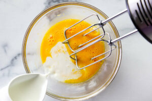 Adding milk to egg yolks for vanilla pudding from scratch.