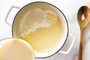 Stirring milk mixture into the sugar for vanilla pudding from scratch.