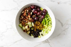 Adding celery, grapes and raisins to apples.
