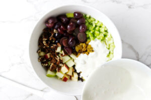 Adding the dressing to a apple waldorf salad.