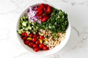 Salad ingredients in a bowl to make bean salad.