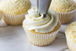 Swirling white chocolate cream cheese on top of cupcakes.