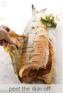 Removing the skin from a whole baked salmon.