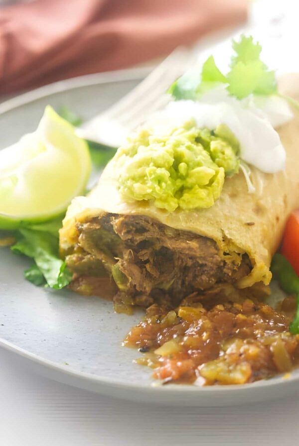 Beef chimichanga with guacamole, sour cream, lime, lettuce, and salsa.