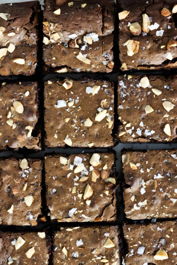 Nine fudgy chocolate brownies topped with almonds and sea salt, from a large batch.