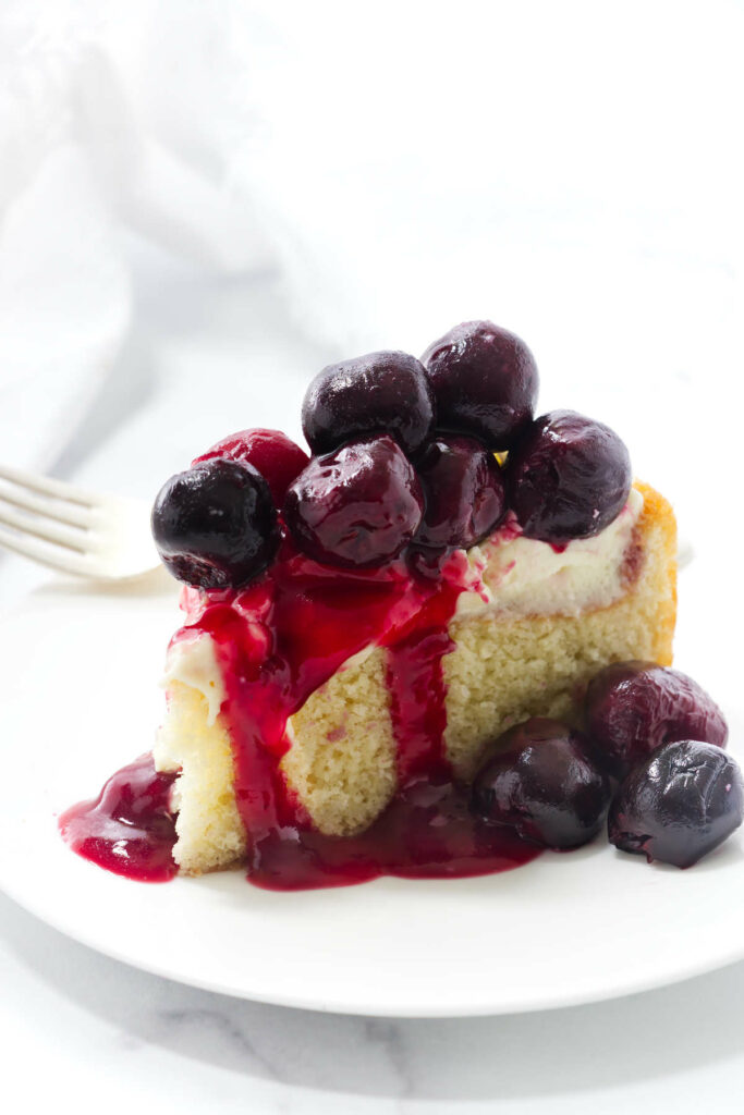 A slice of almond cream cake with cherry compote.