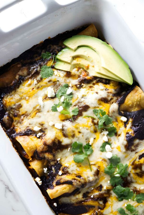 Crowd pleasing shredded chicken enchiladas with mole sauce and avocado.