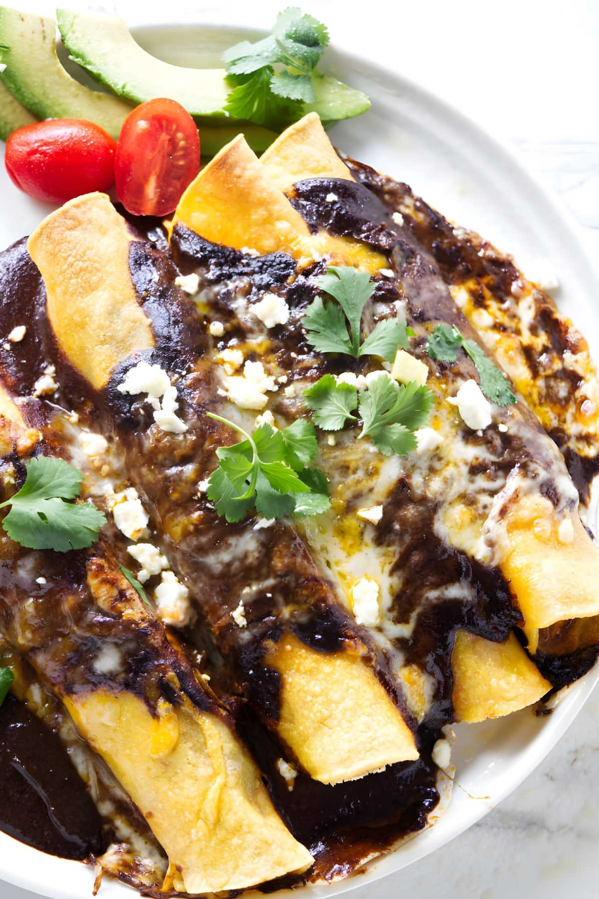 Three Mexican chicken mole enchiladas with cheese, cilantro.