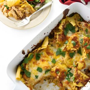 Overhead view of cheesy baked enchiladas with salad and a fork.