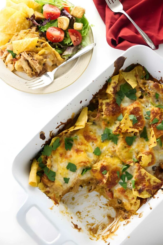 Overhead view of cheesy nacho bake with salad and a fork.