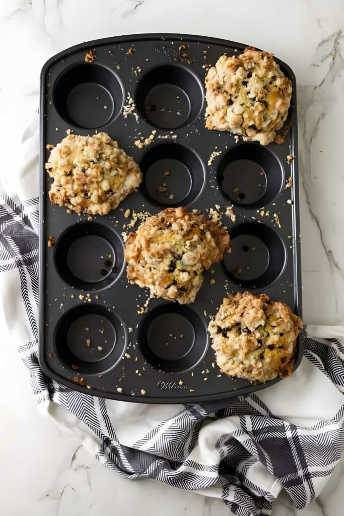 Muffin tin with five muffins topped with streusel.