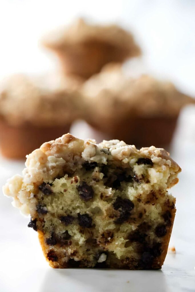 A halved chocolate chip muffin with crumbly topping and moist interior.