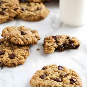 Oatmeal chocolate chip cookies with milk; one cookie broken showing gooey center.