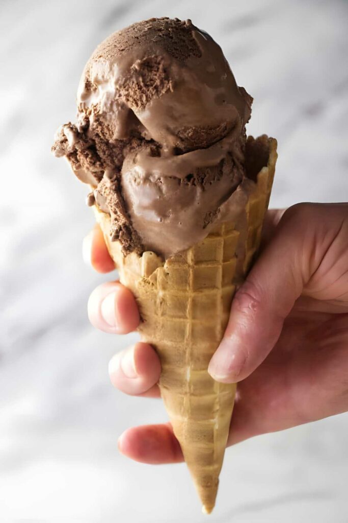 chocolate stout ice cream Hand holding waffle cone with two scoops of stout beer chocolate ice cream.