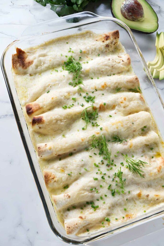 Baked crab meat enchiladas with melted cheese and herbs in a baking dish.
