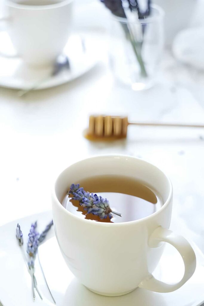 A tea cup with lavender garnish, honey dipper, and lavender vase.