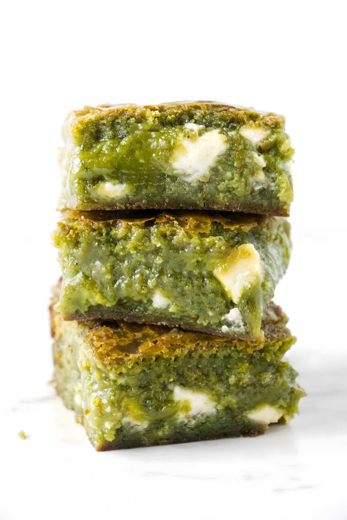 Stack of three gooey green matcha brownies with white chocolate chunks.