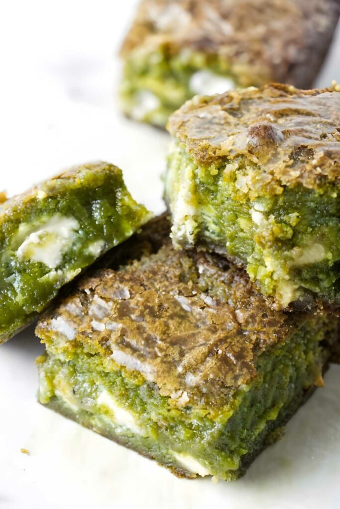 Three green matcha brownies with white chocolate chunks.