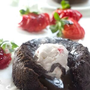 Chocolate lava cake with melting center, vanilla ice cream, strawberries garnish.