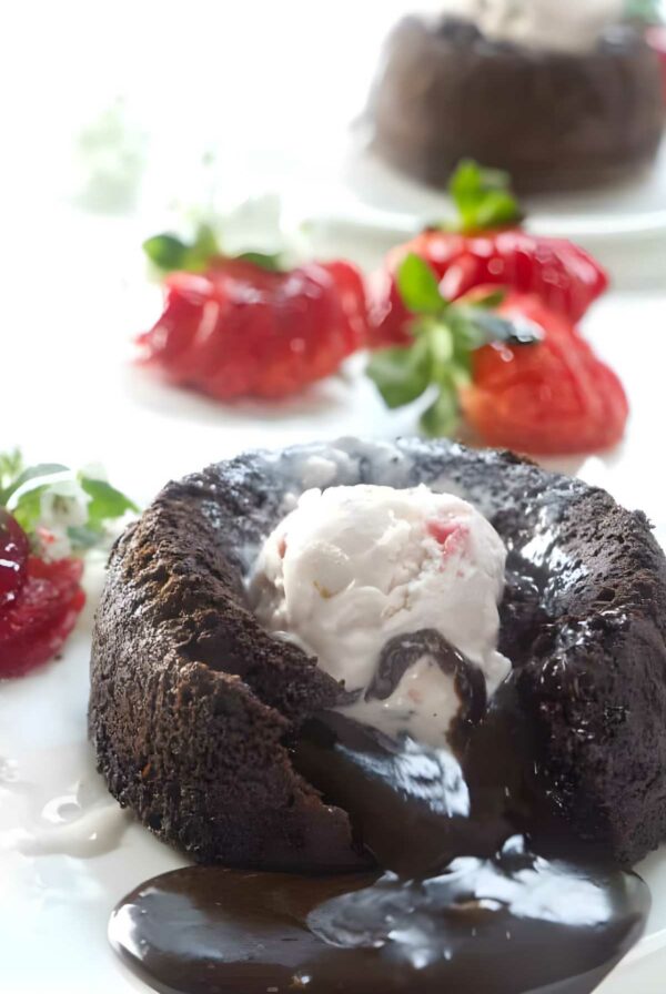 Chocolate lava cake with melting center, vanilla ice cream, strawberries garnish.