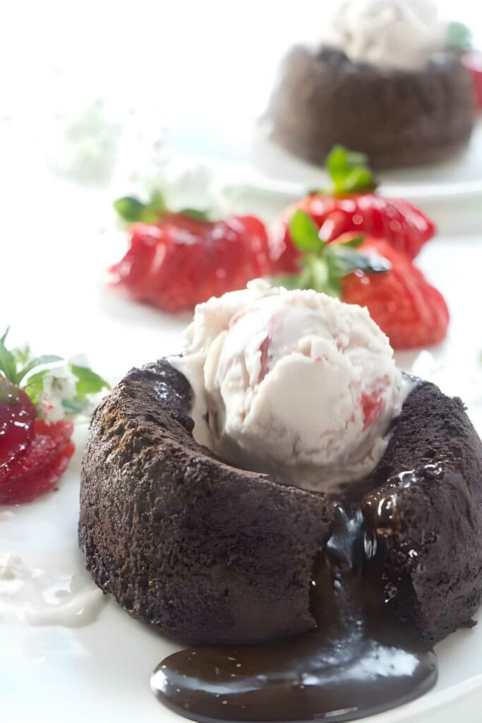 Molten chocolate lava cake with ice cream, strawberries, and whipped cream.