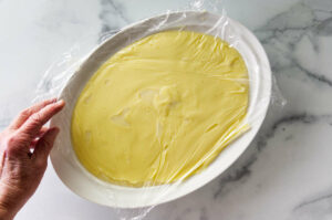 Covering a bowl of homemade custard to cool for the buttercream.