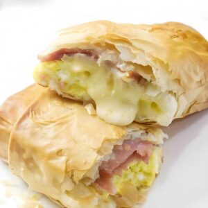 Cut-open phyllo pastry with gooey ham, egg, and cheese filling.