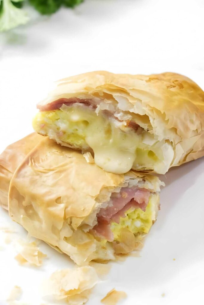 Cut-open phyllo pastry burrito with gooey ham, egg, and cheese filling.