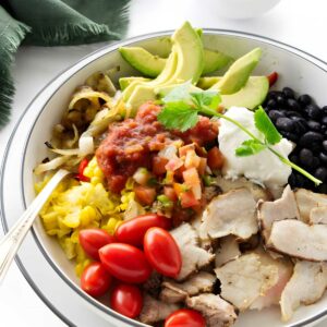 A fajita bowl with pork, tomato, beans, and corn.