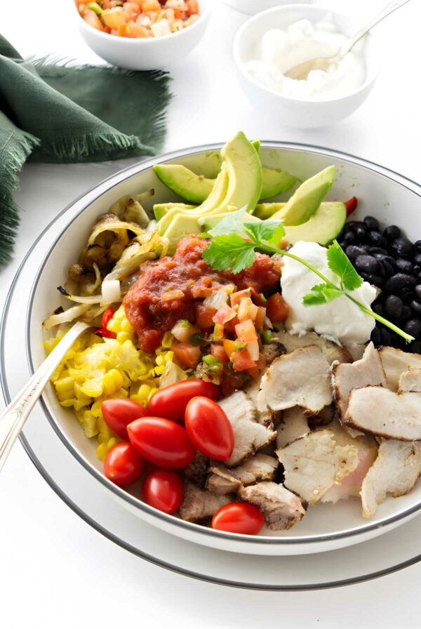A fajita bowl with pork, tomato, beans, and corn.