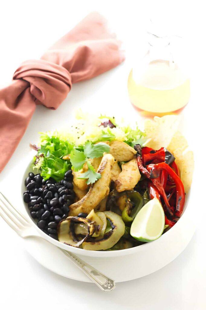 Chicken fajita fixings in a bowl next to a napkin.