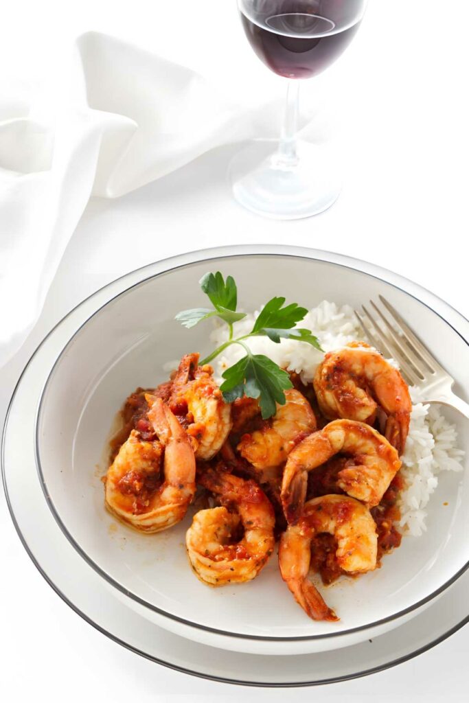 Spicy shrimp in tomato sauce over rice, garnished with parsley.