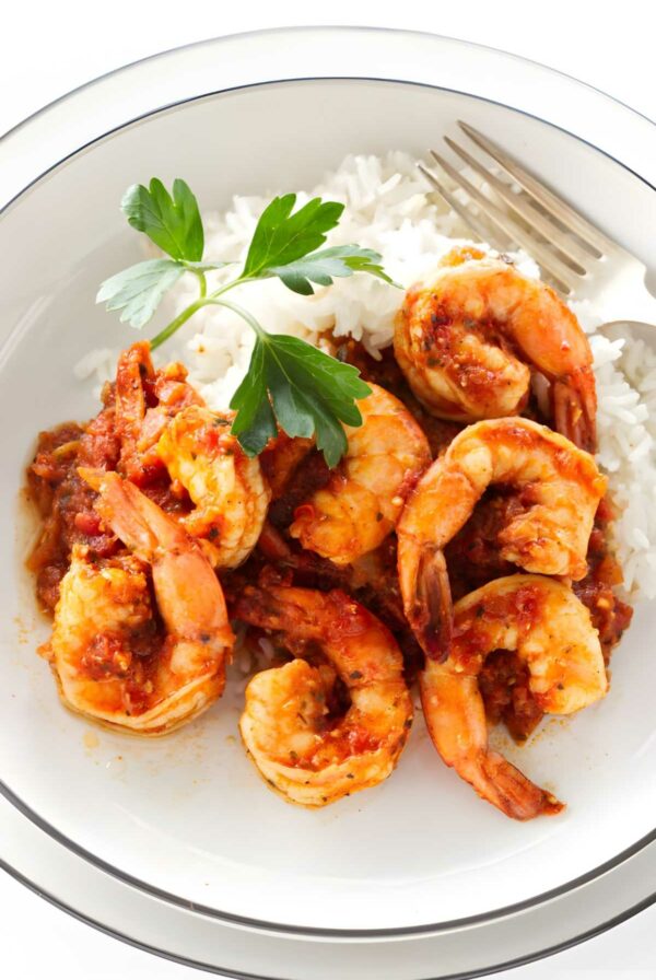 Shrimp diablo in tomato sauce over rice, garnished with parsley.